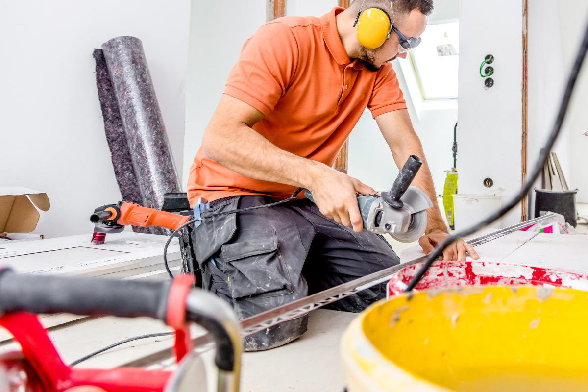 Ein Handwerker schneidet mit einem Winkelschneider eine Fliesenschine